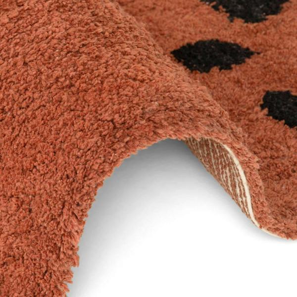 Close-up of a brown doormat with black paw prints on a white background