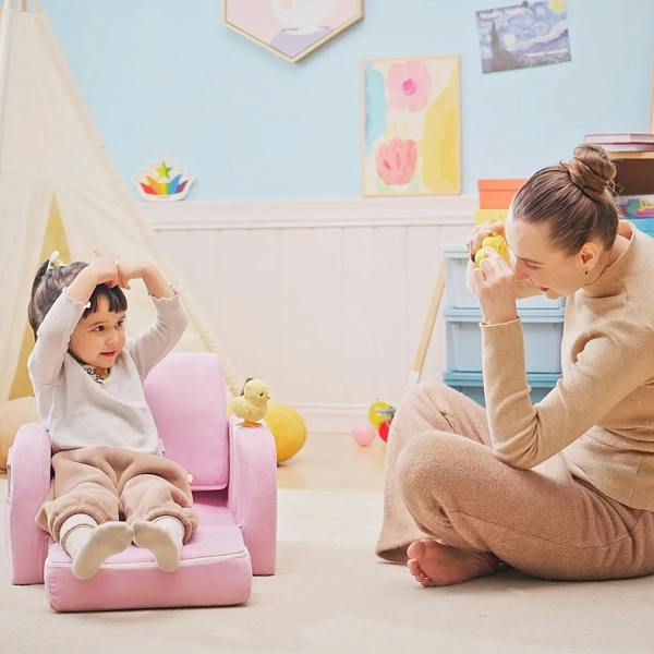 Pink kids armchair with a child seated, soft fabric upholstery and rounded armrests
