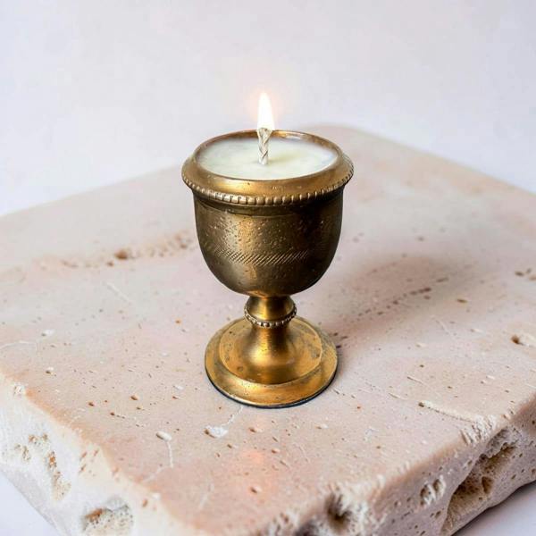 Candle in a decorative brass holder on a stone surface