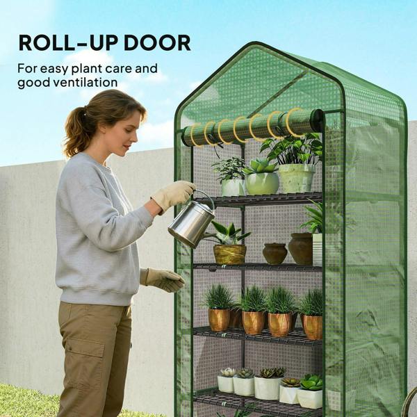 Green mini greenhouse with roll-up door open for ventilation and five wire shelves inside.