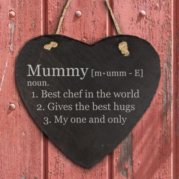 A heart-shaped black slate plaque engraved with a dictionary definition for 'Mummy' hanging by a jute rope against a rustic red wooden background.