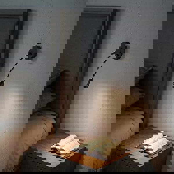 black gooseneck reading light installed next to the bed on the wall in a modern bedroom