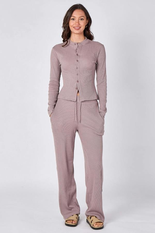 Woman wearing a matching purple cardigan and pants set on a white background