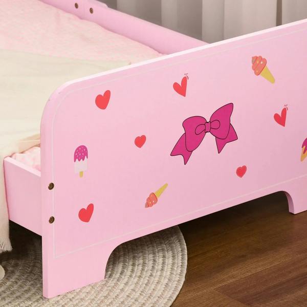Pink toddler bed side panel with heart and bow prints; low guardrail opening for kids