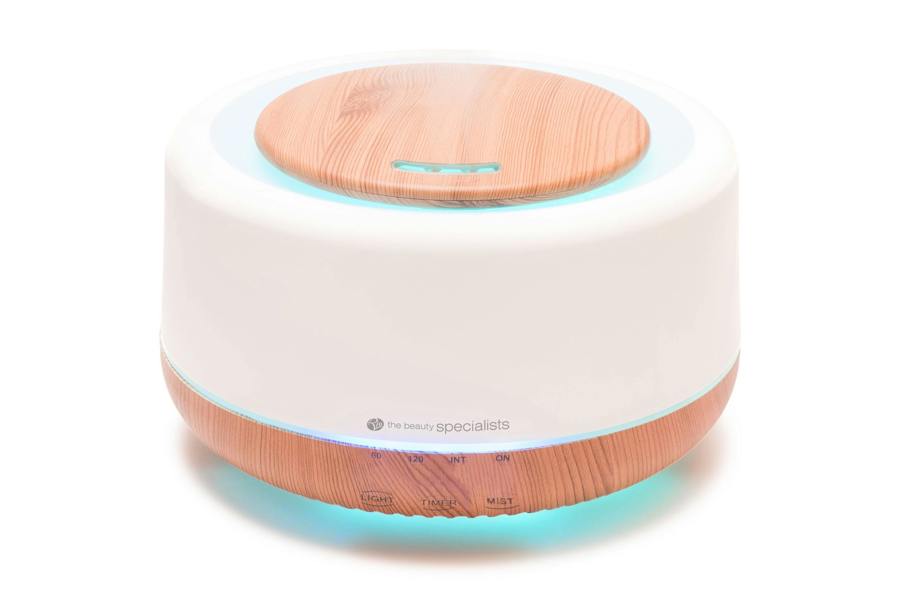 The Rio ALORA Aroma Diffuser is a round, modern device with a white and wood-grain look. It functions as a humidifier and night-light, featuring front buttons and indicator lights to enhance your space with soothing scents and balanced moisture.