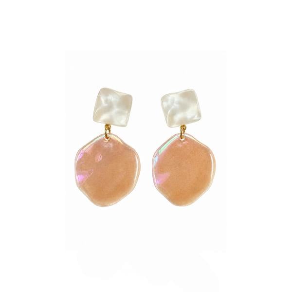 A pair of dangling earrings with iridescent peach-pink irregular disc charms and white square stud tops, connected by small gold rings, shown on a plain white background.