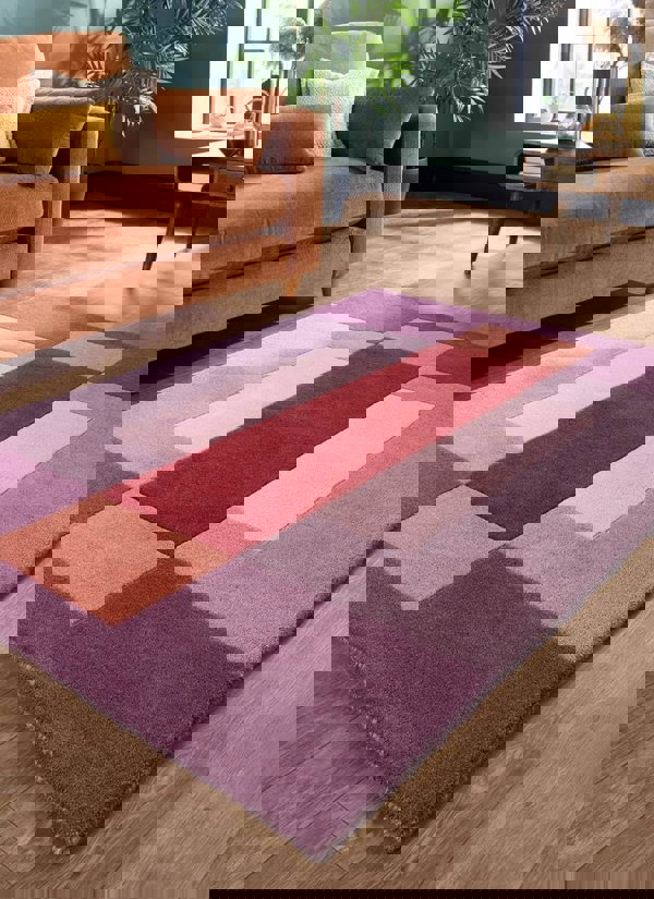 Hand-carved multicolour geometric wool rug in modern living room with orange sofa and decorative pillows.