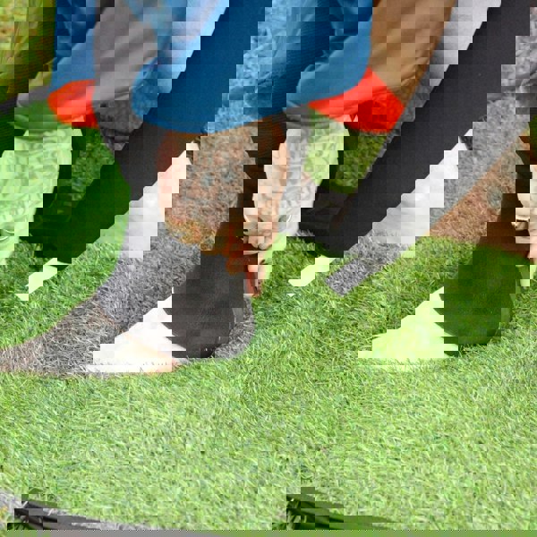 Person adjusting a black foot device on a green grass surface