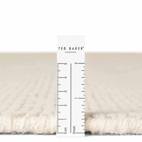 Close-up of a textured fabric with a ruler and 'Ted Baker London' label.