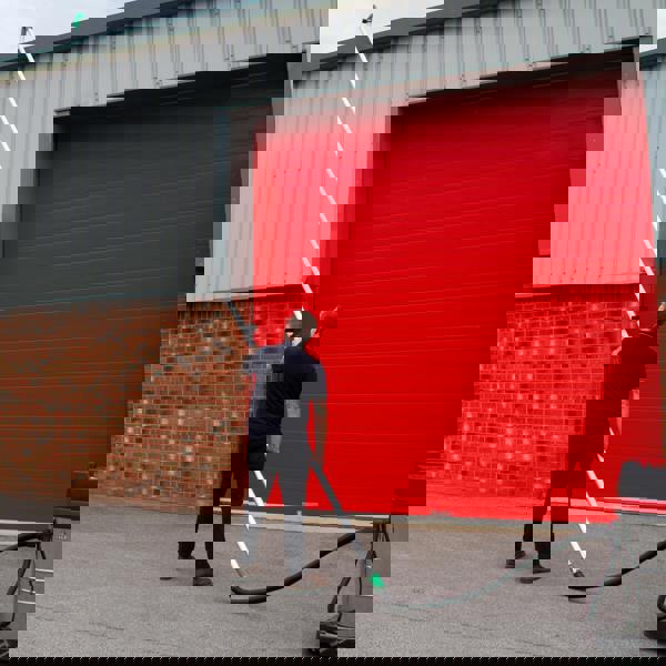 80L wet and dry vacuum with long gutter vacuum poles, user positioned against a bright red garage door, showcasing versatility and reach