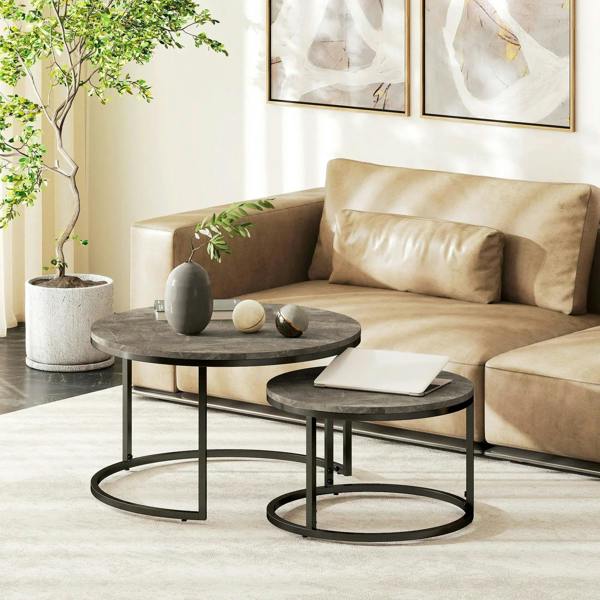 Two round nesting coffee tables with dark faux-marble tops and black steel frames
