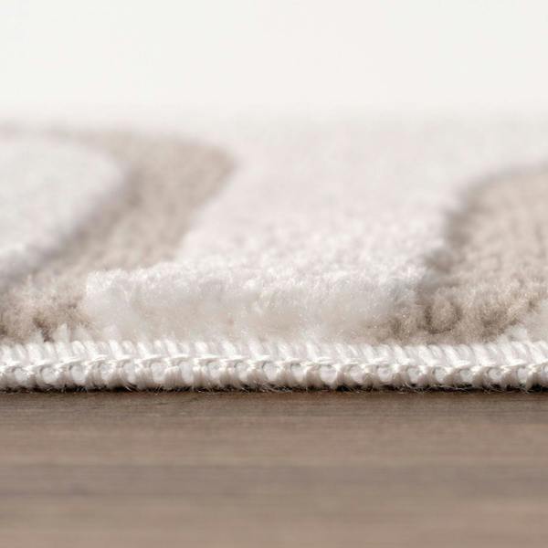 Close-up of a textured rug with a neutral color palette on a wooden floor.