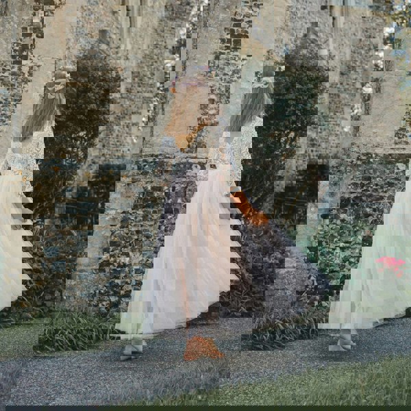 girl in a white dress standing in front of an old stone building