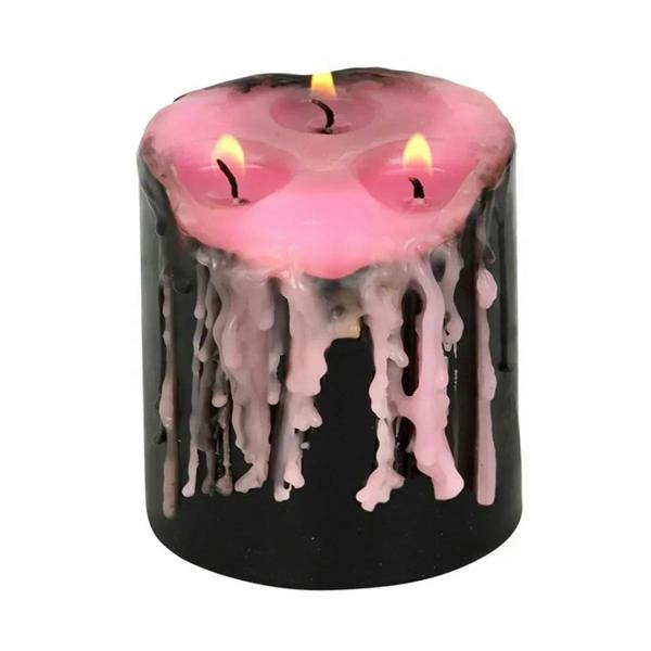 Black pillar candle with pink wax pool and long pink drip detail, three lit wicks