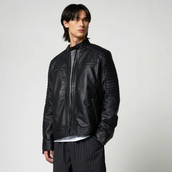 Image shows a male model wearing a real leather jacket by Barneys Originals. The jacket is a classic racer design with a buckle collar, central zipline, two chest pockets and ribbed shoulder detail which runs down to the elbow crease.