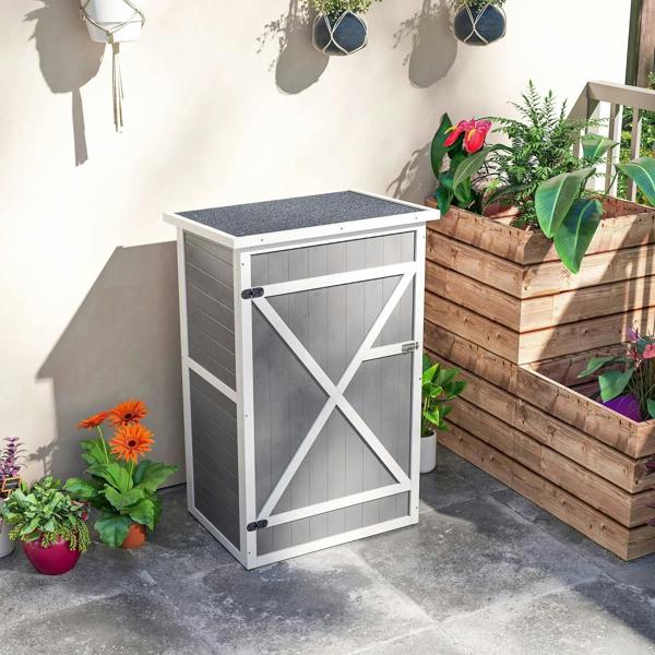 Grey wooden small storage shed with white X-brace door, closed on patio beside planters