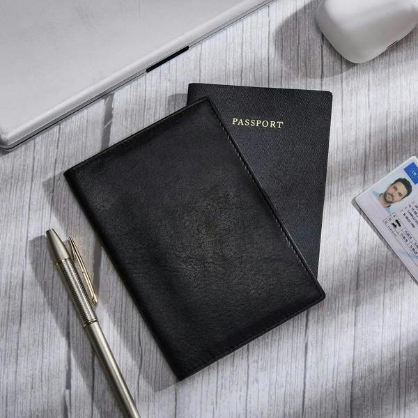 Black passport holder with a passport and ID card on a wooden surface.