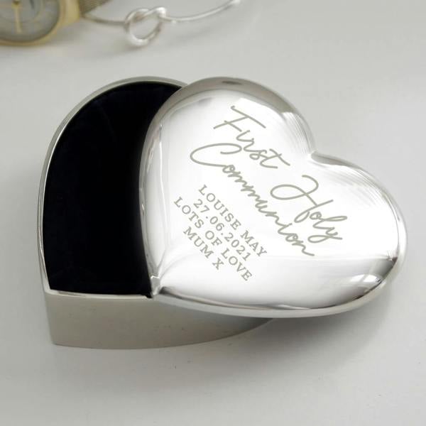 A polished silver heart-shaped trinket box engraved with 'First Holy Communion Louise May 27.06.2021 Lots of Love Mum x' with a soft dark velvet interior.