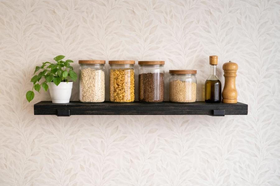 Ebony stained reclaimed scaffold board shelf styled in kitchen with jars and plant