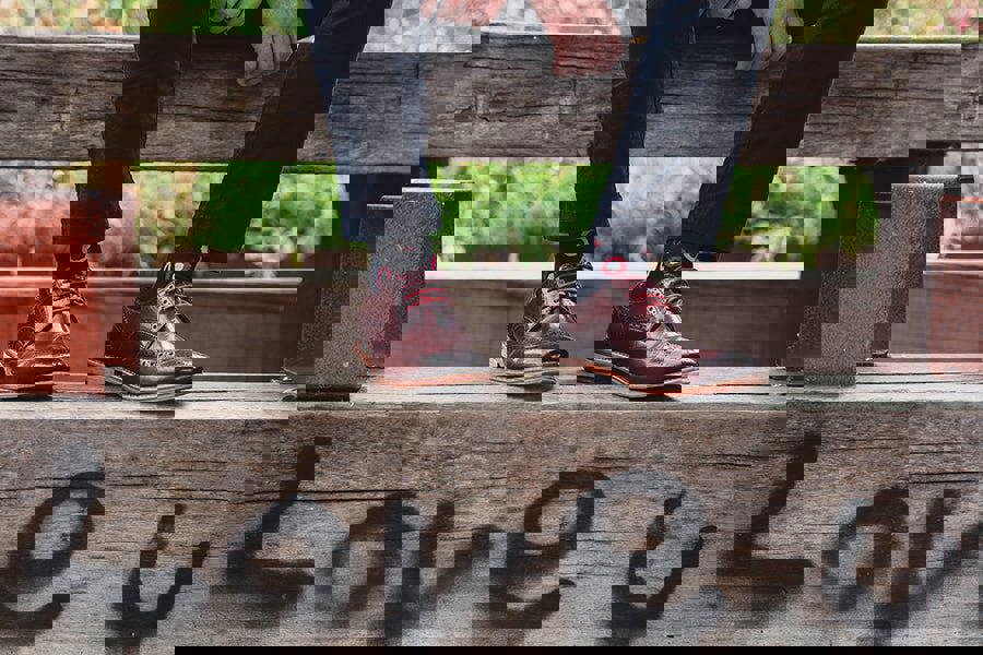 Dark Red Brogue Shoes with Navy Socks sat on wooden bench