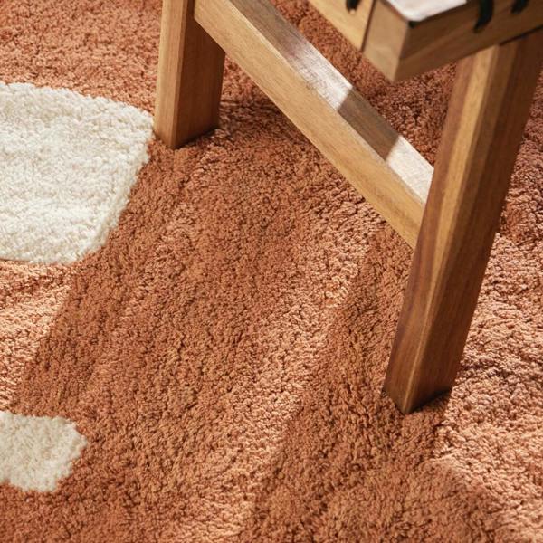 Close-up of a brown carpet with a wooden chair leg