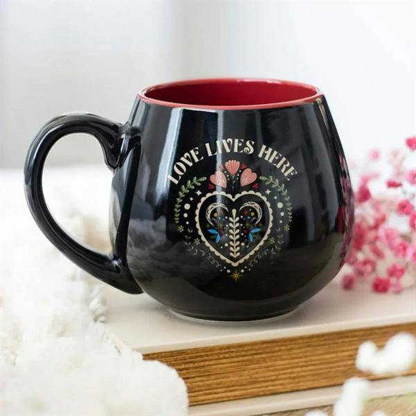 Black ceramic mug with red interior, folk heart print, and C-shaped handle