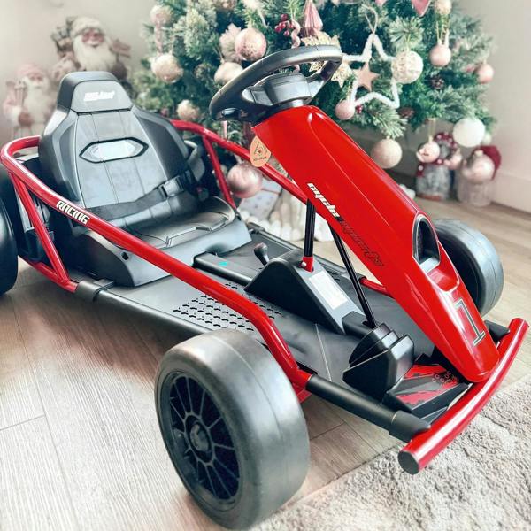Red electric kids go-kart close-up with black seat and steering wheel, side angle