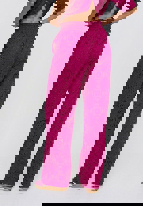 Person wearing magenta patterned pants on a white background