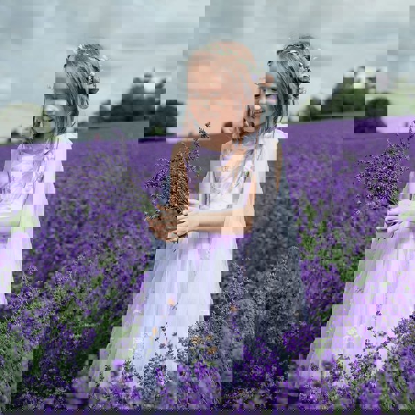 Young girl in a lavender field holding a bouquet of lavender flowers.