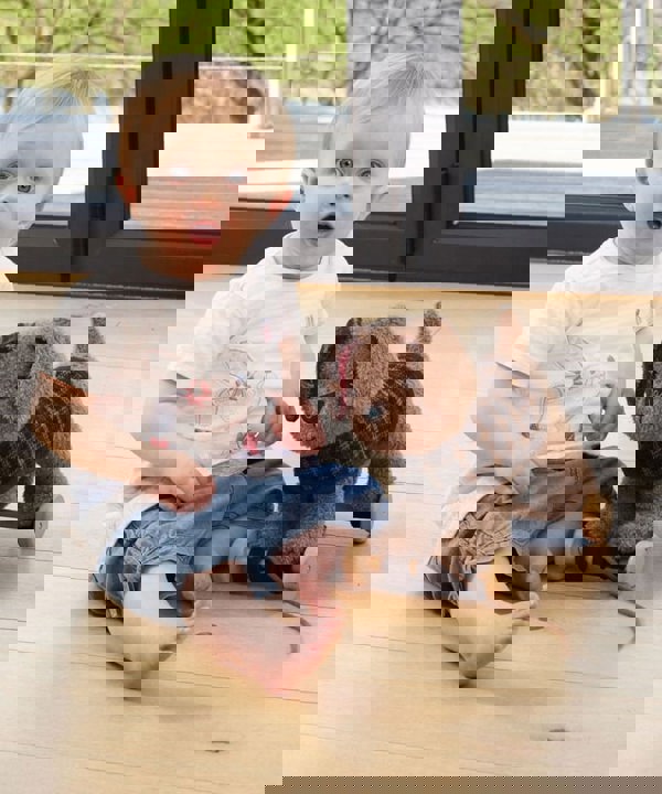 Girl sitting with Percy Pup Pull Along Toy