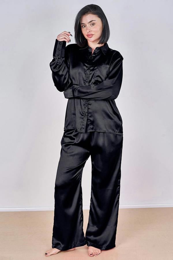 Woman wearing a black satin pajama set against a plain background