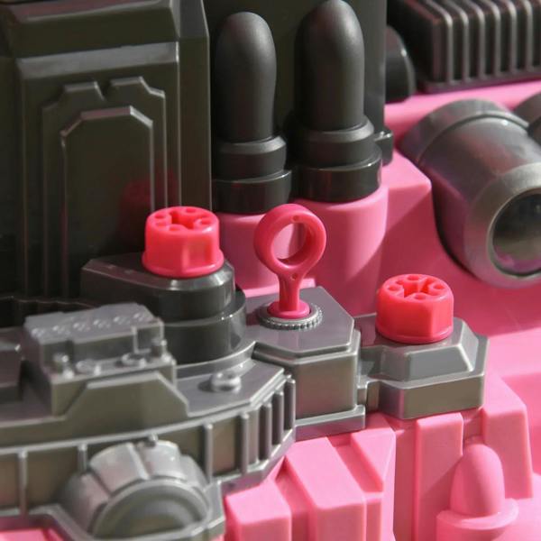 Close-up of pink-and-gray toy engine parts with red knobs and circular details.