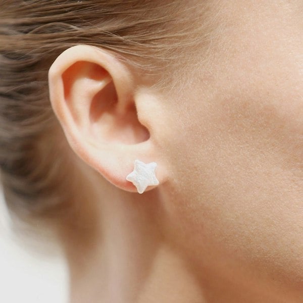 An ear with star pearl stud earrings.