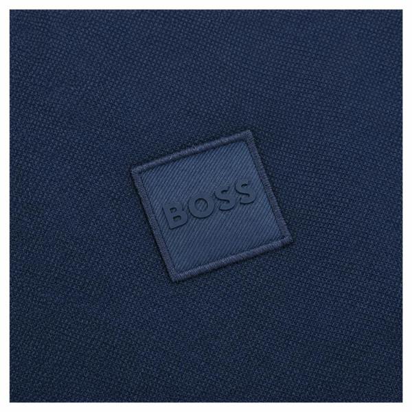 Navy blue BOSS polo shirt featuring a textured fabric and a matching square logo patch with embossed lettering.