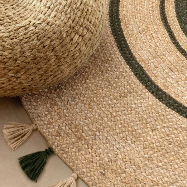 Woven jute rug with tassels and a textured ottoman on a neutral background