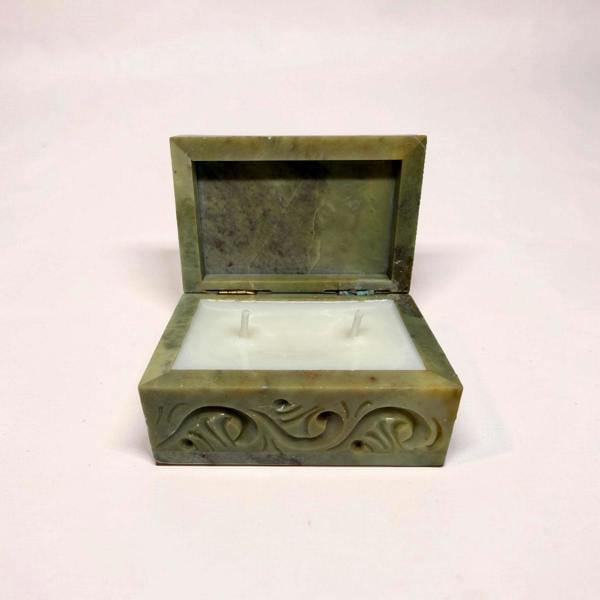 Decorative green box with a candle inside on a white background