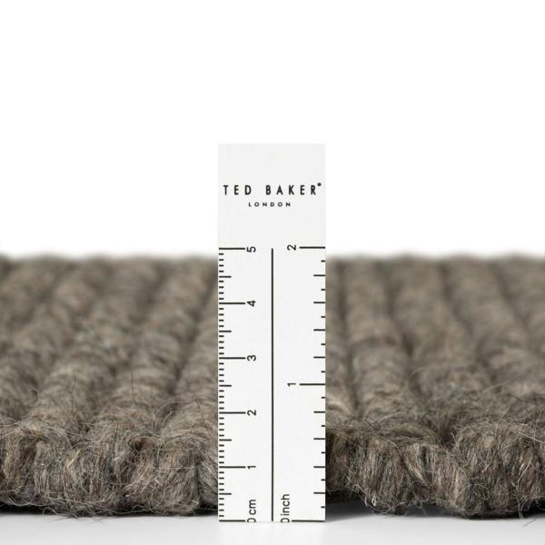 Close-up of a textured fabric with a ruler and 'Ted Baker London' label.