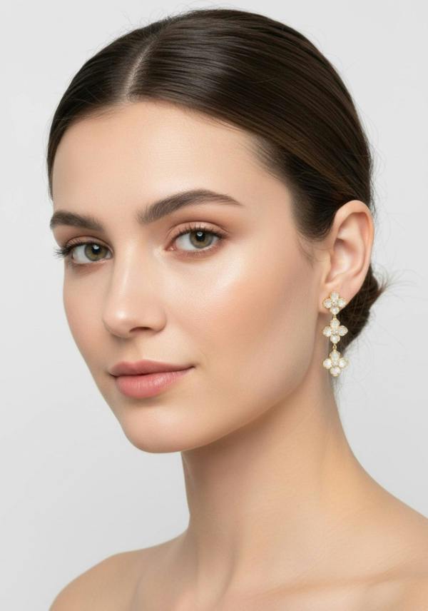 Woman wearing white clover earrings on a plain background
