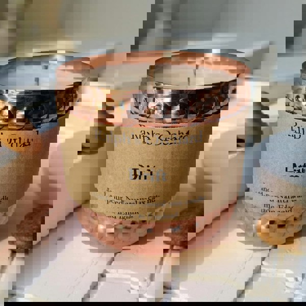 Candle with a copper lid and 'Ralph's Orchard Drift' label on a light surface.