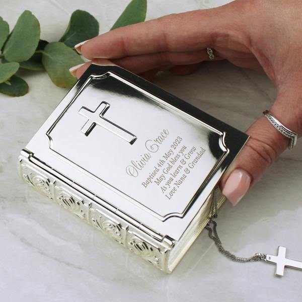 A hand holding a personalised nickel-plated Bible trinket box engraved for a baptism with the name Olivia Grace.