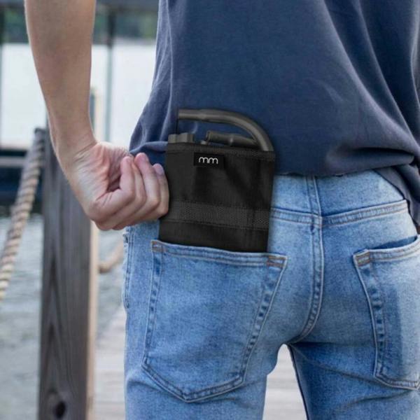 A close-up view of a person slipping a compact, black folded metal and nylon stool neatly into the back pocket of their blue jeans.