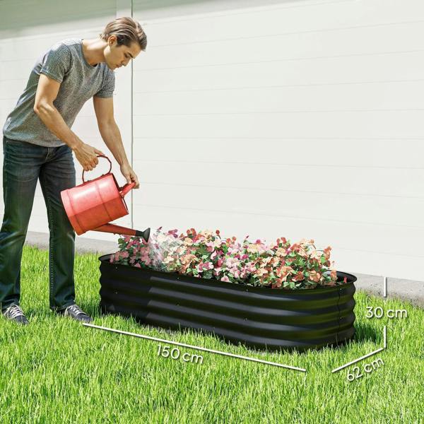 Black raised garden bed planter box being filled with flowers in a lawn setting