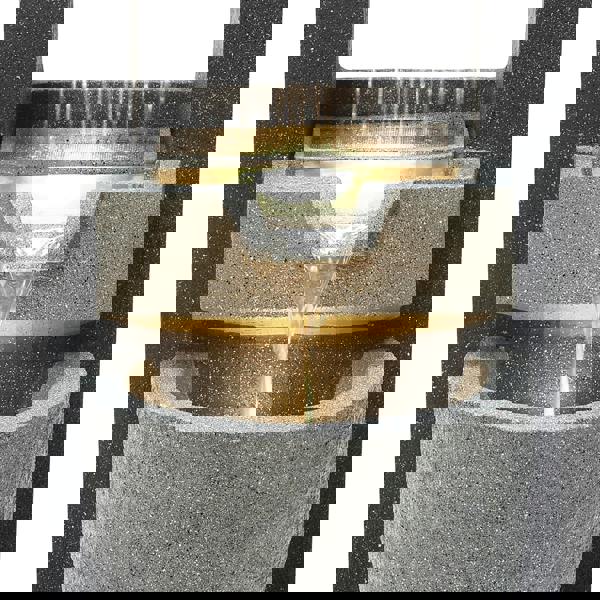 Elegant electric water feature with cascading water, textured gray stone finish, and soft glowing light illuminating the flow