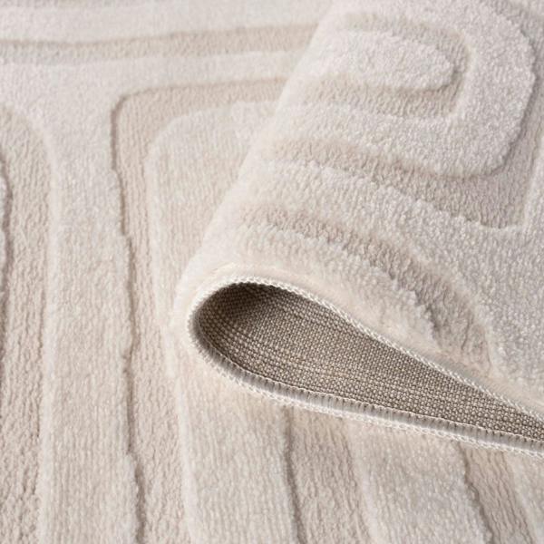 Close-up of a textured beige bath mat with a folded corner.
