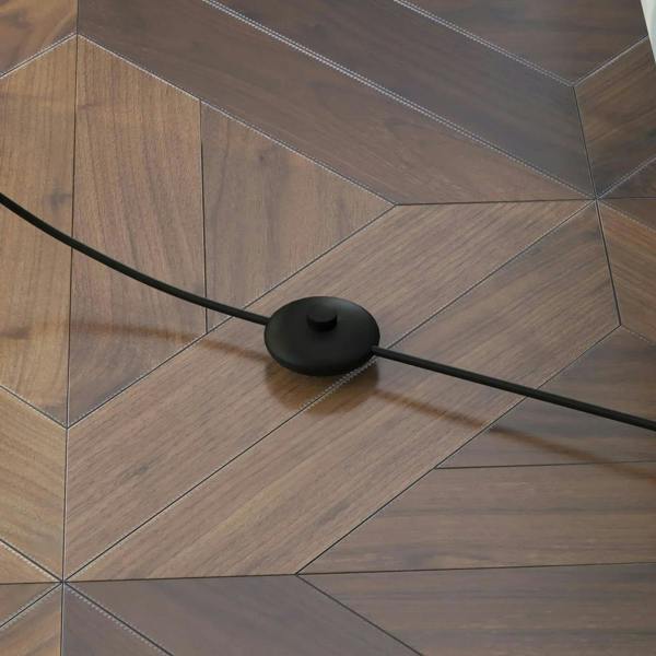 Black round base and cord weight for a standing lamp on tiled flooring