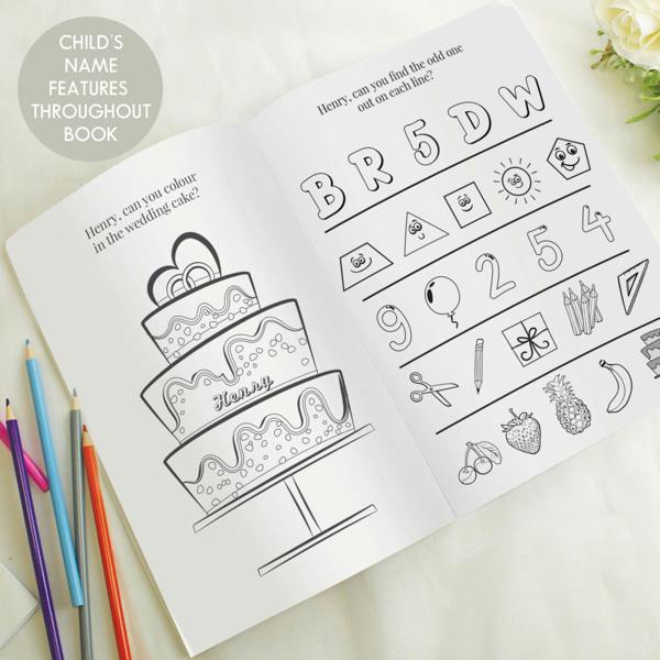 An open personalised blue wedding activity book displays two internal pages on a light background. The left page features a tiered wedding cake graphic with the name 'Henry' styled into the middle tier, underneath the text 'Henry, can you colour in the wedding cake?'. The right page contains an odd-one-out puzzle reading 'Henry, can you find the odd one out on each line?'. A grey circle in the upper left reads 'Child's Name Features Throughout Book'.