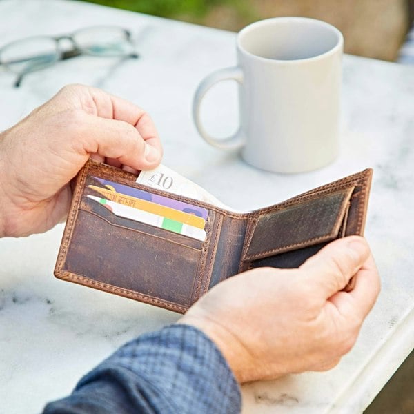 A man holding a Personalised Buffalo Leather Billfold Wallet and a cup of coffee.