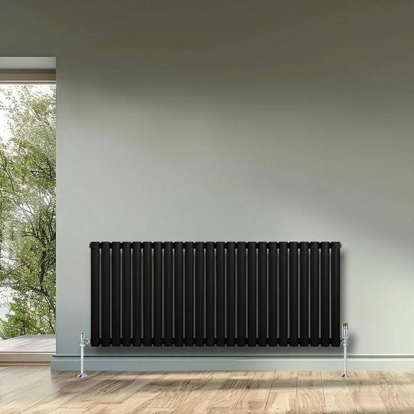 Sleek black oval single column radiator with chrome valves, mounted on a light wall, enhancing modern interior decor