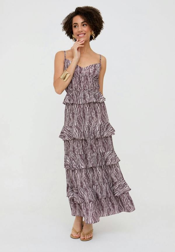 Woman wearing a tiered, patterned dress on a white background