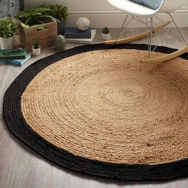 Round jute rug with black border on a wooden floor, surrounded by decorative items.